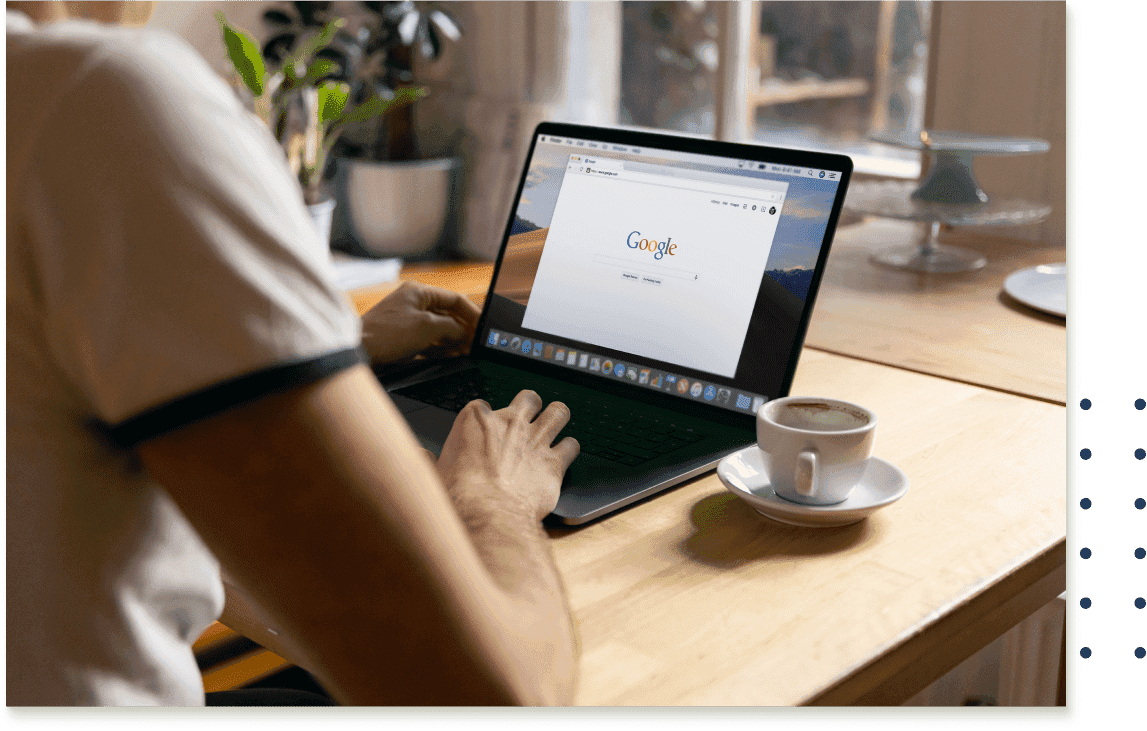 A person sitting at a table with a tea cup and a laptop with google search on the screen