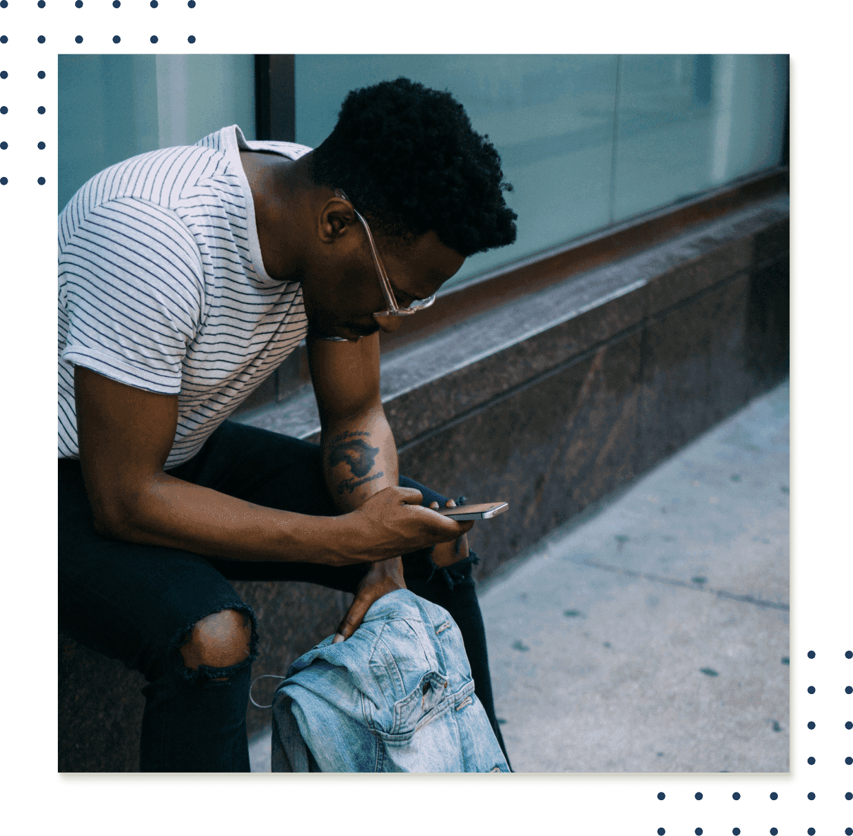 A man looking at a cellphone sitting on a windowsill outside a building